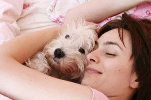 Woman curled up and sleeping with dog CanadianPharmacyMeds.com