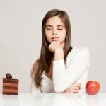 Woman choosing between cake and an apple CanadianPharmacyMeds.com